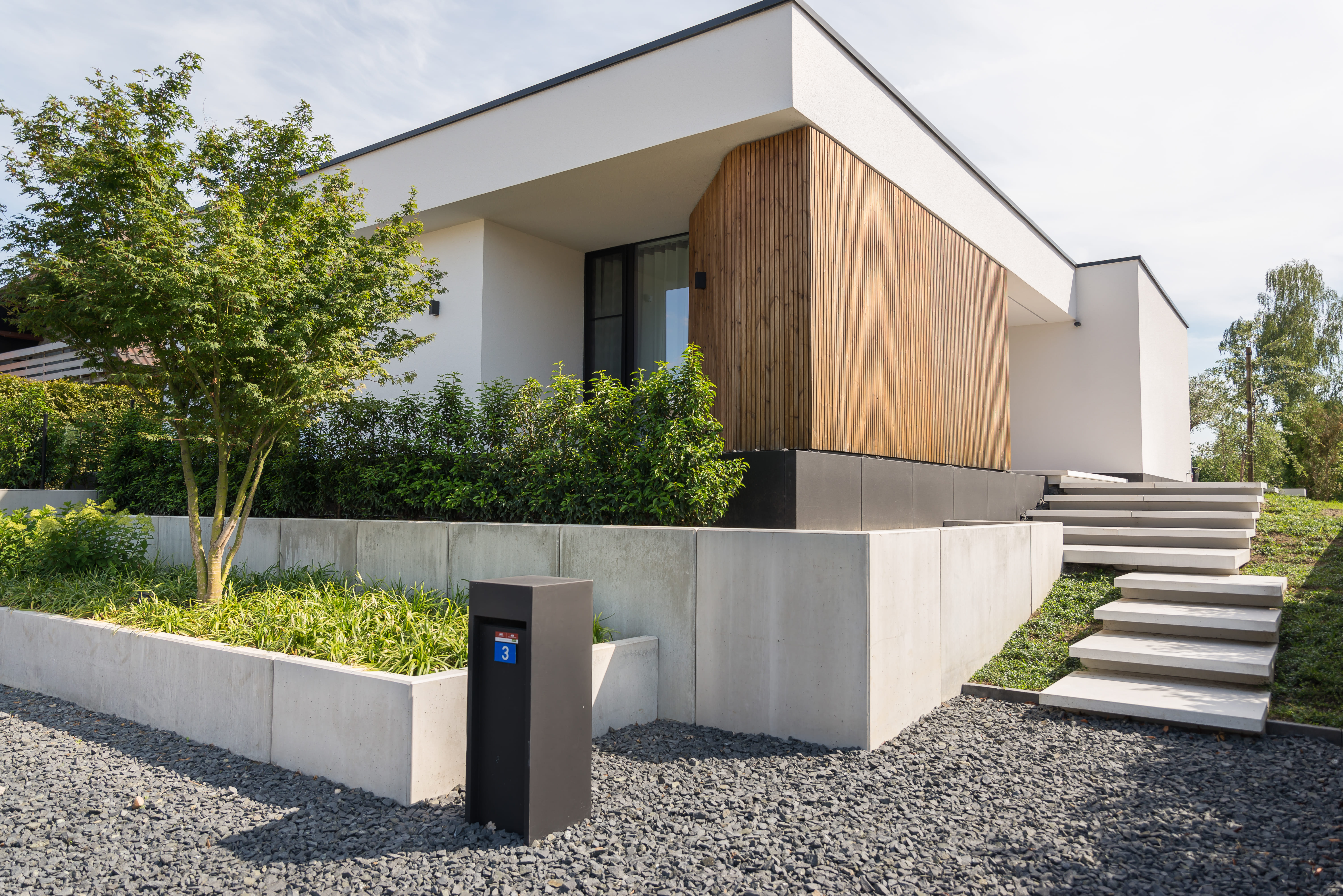 De voortuin van een woning met verschillende keermuren om hoogteverschil te overbruggen.